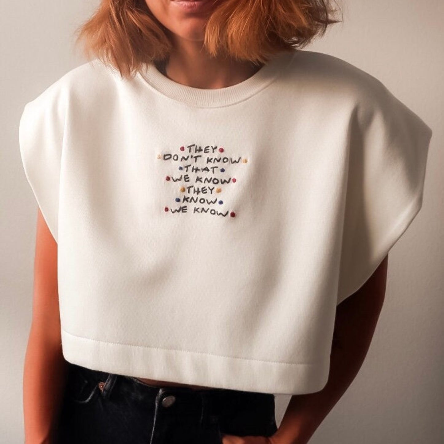 Person wearing a white crop top with text design against a plain background