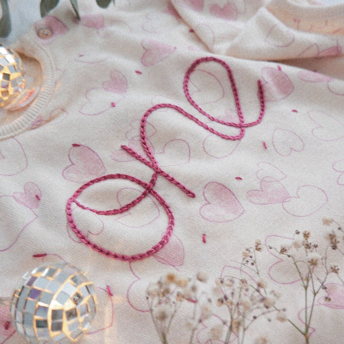 Baby blanket with 'love' embroidery and heart patterns, surrounded by decorative elements.