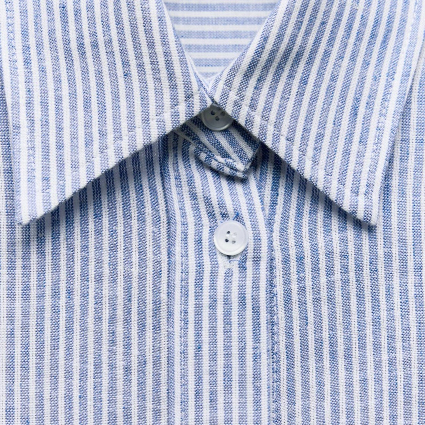 Close-up of a blue and white striped shirt with a button detail.