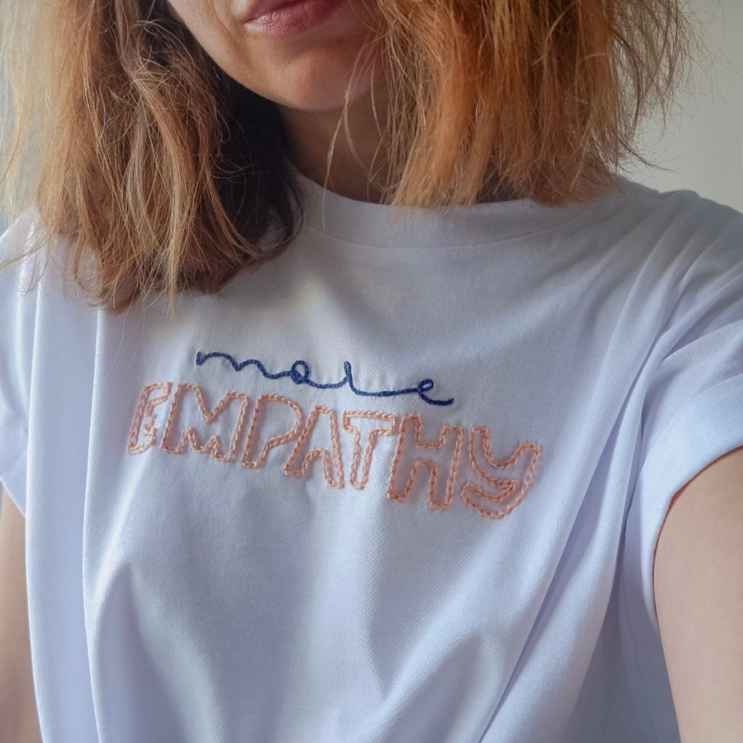White t-shirt with 'more empathy' text on a plain background