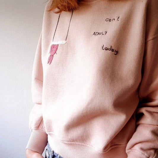 Person wearing a pink sweatshirt with text and a graphic design.