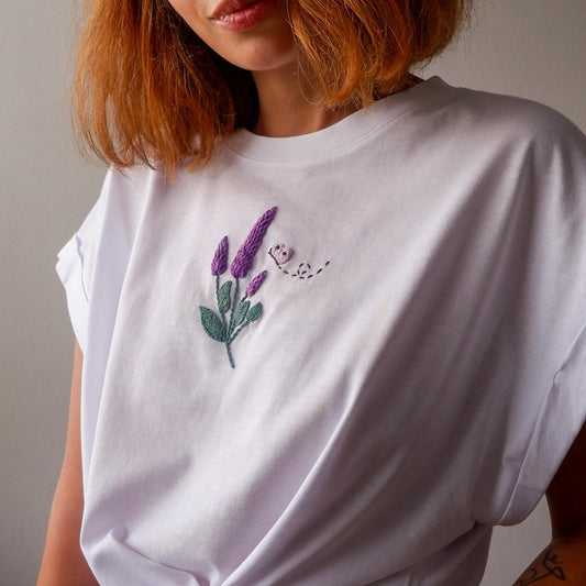 White t-shirt with embroidered lavender design worn by a person.