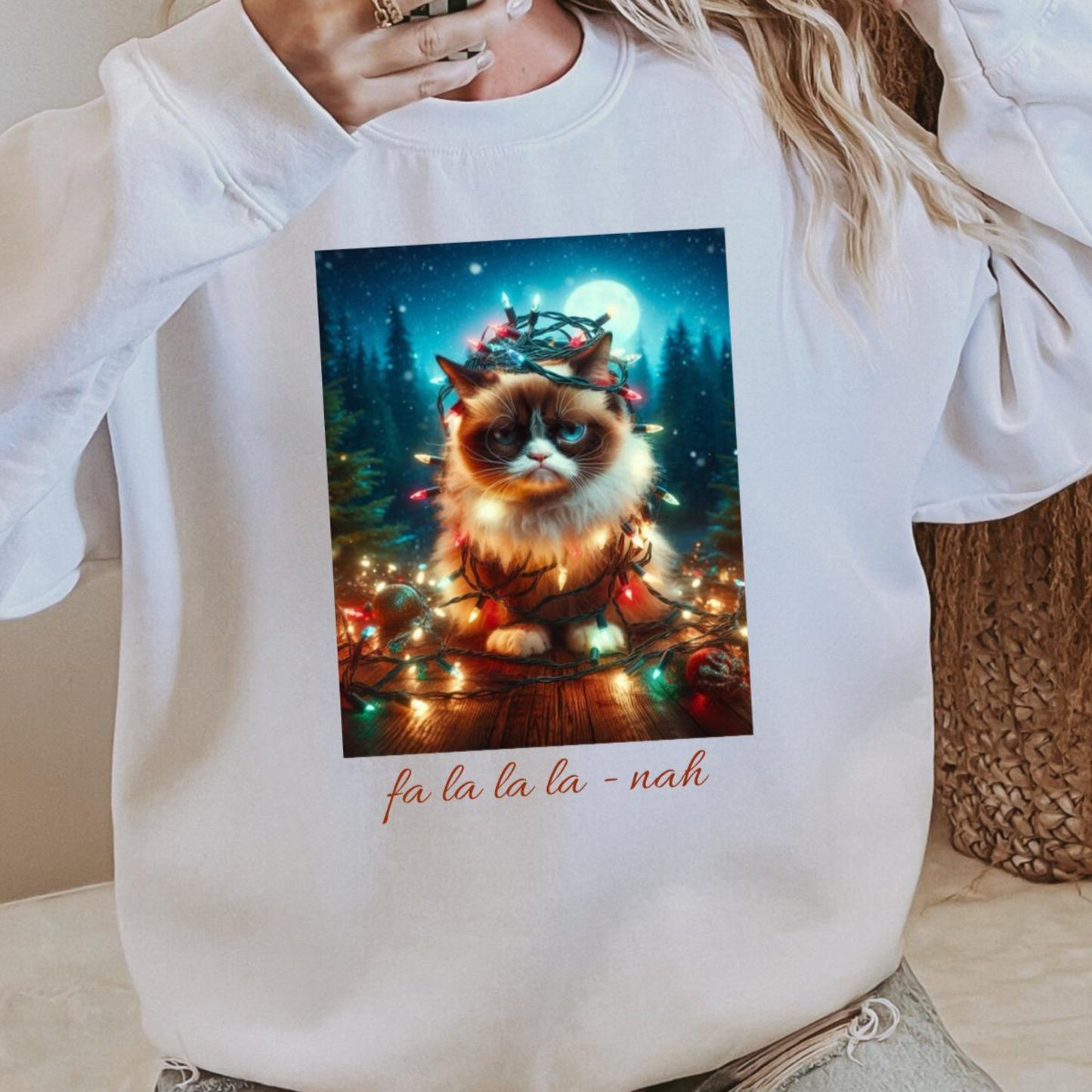 Person wearing a white sweatshirt with a Christmas-themed cat graphic and text.