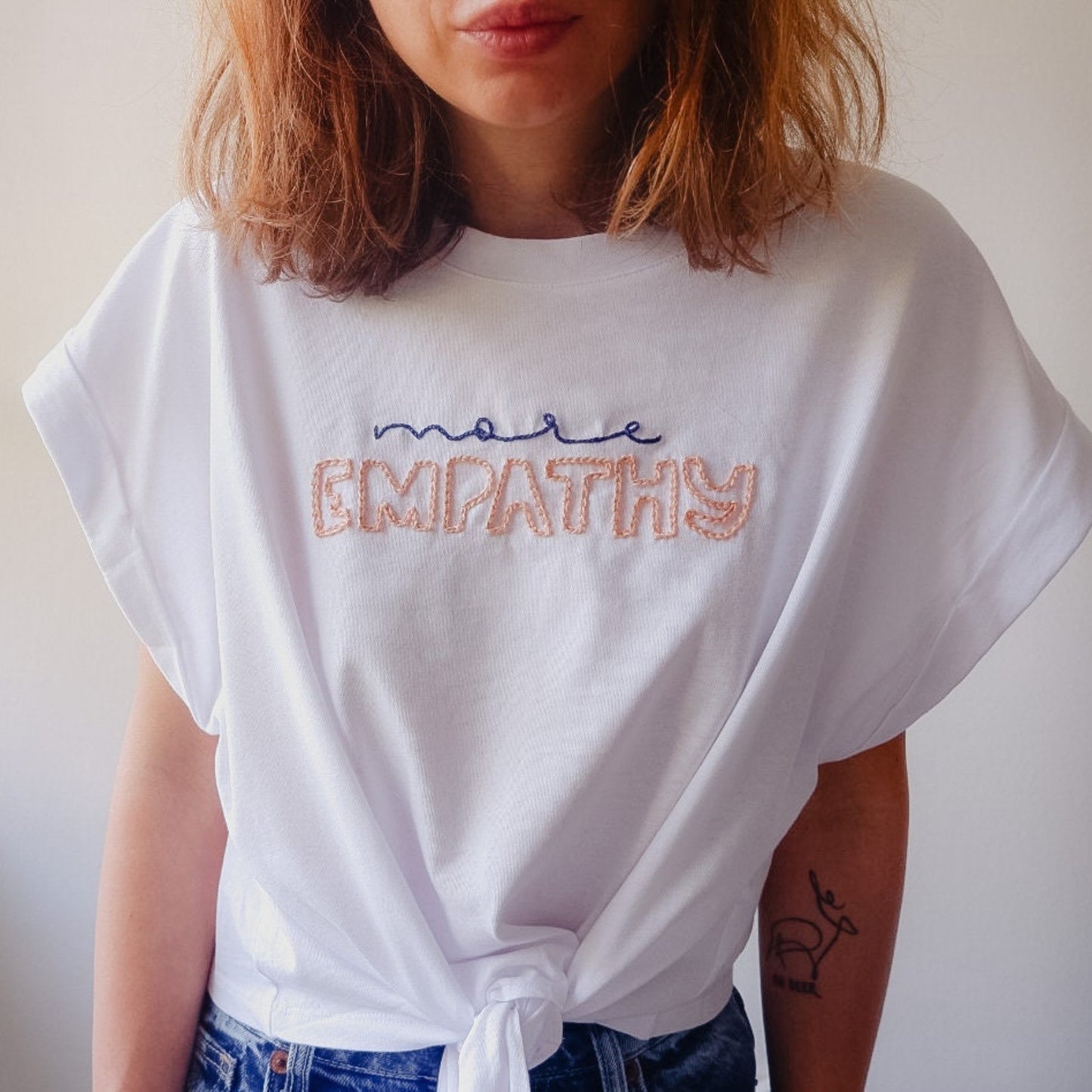 Person wearing a white t-shirt with 'more empathy' text.