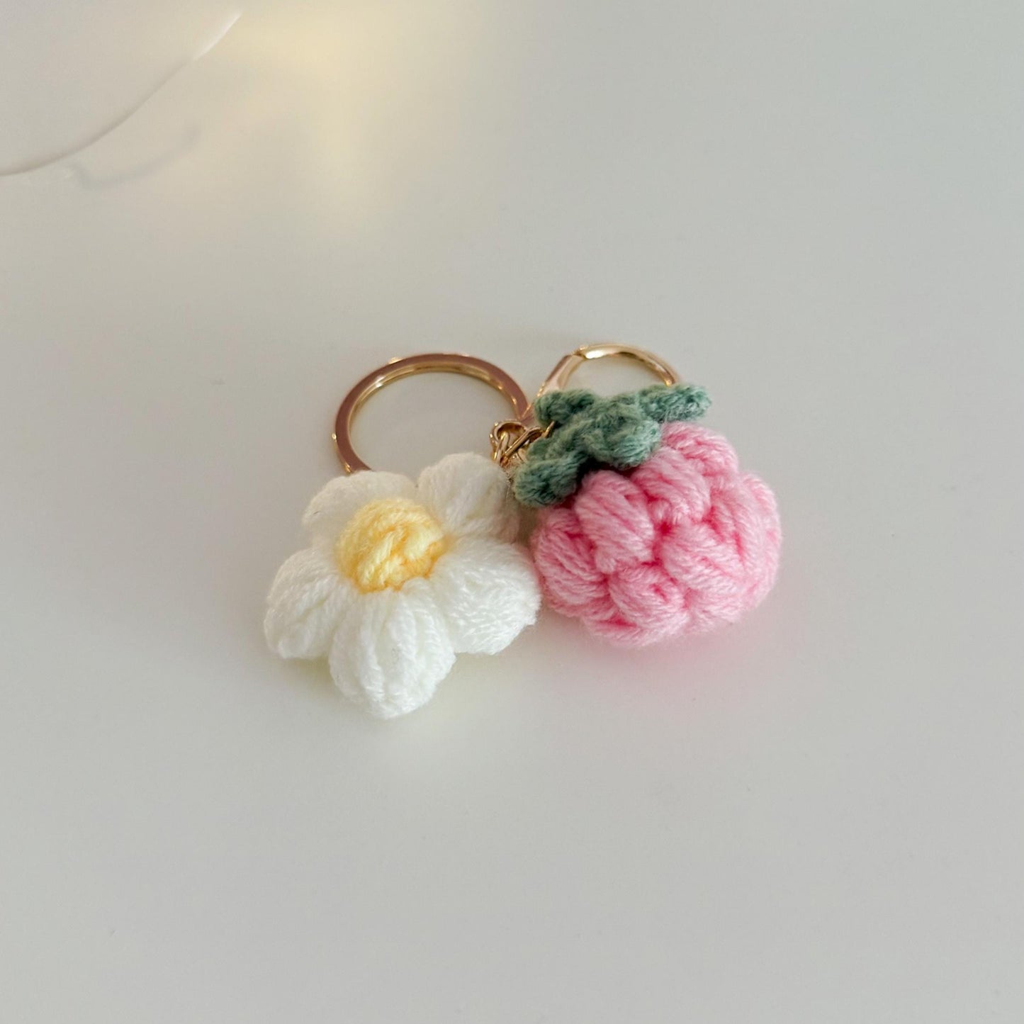 Handmade keychain with a pink flower and white daisy on a light gray background