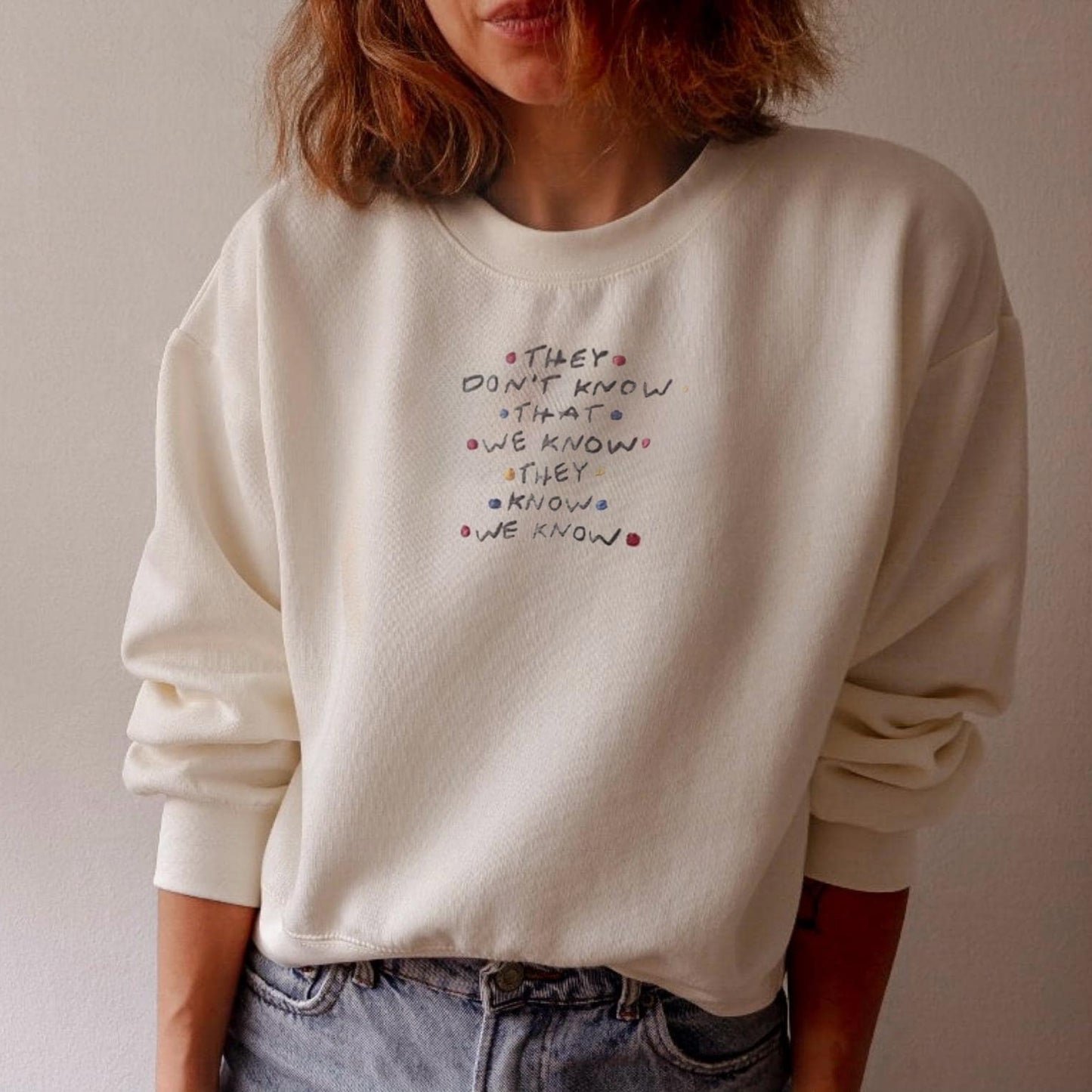 Person wearing a white sweatshirt with text design against a plain background