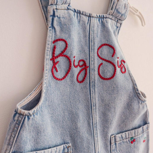 Denim overalls with 'Big Sis' embroidery on a white background