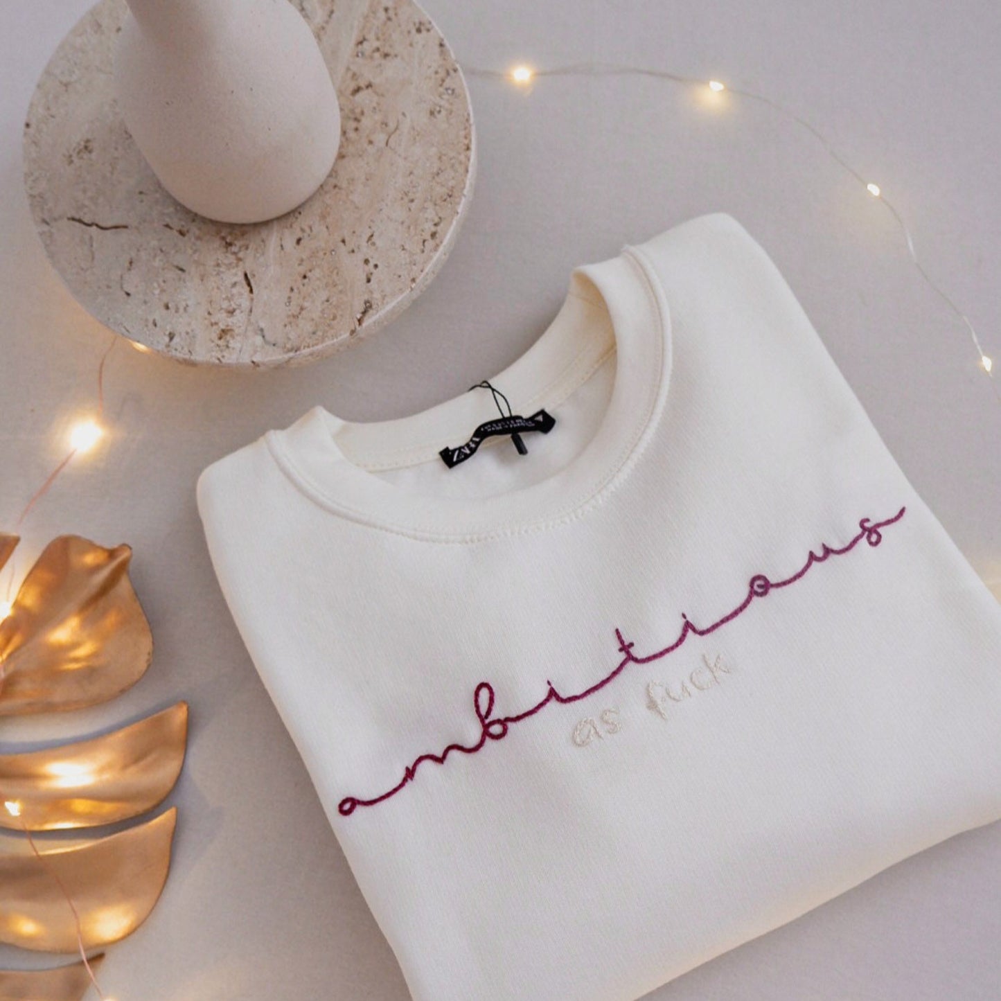 White sweatshirt with red text on a light surface with decorative elements