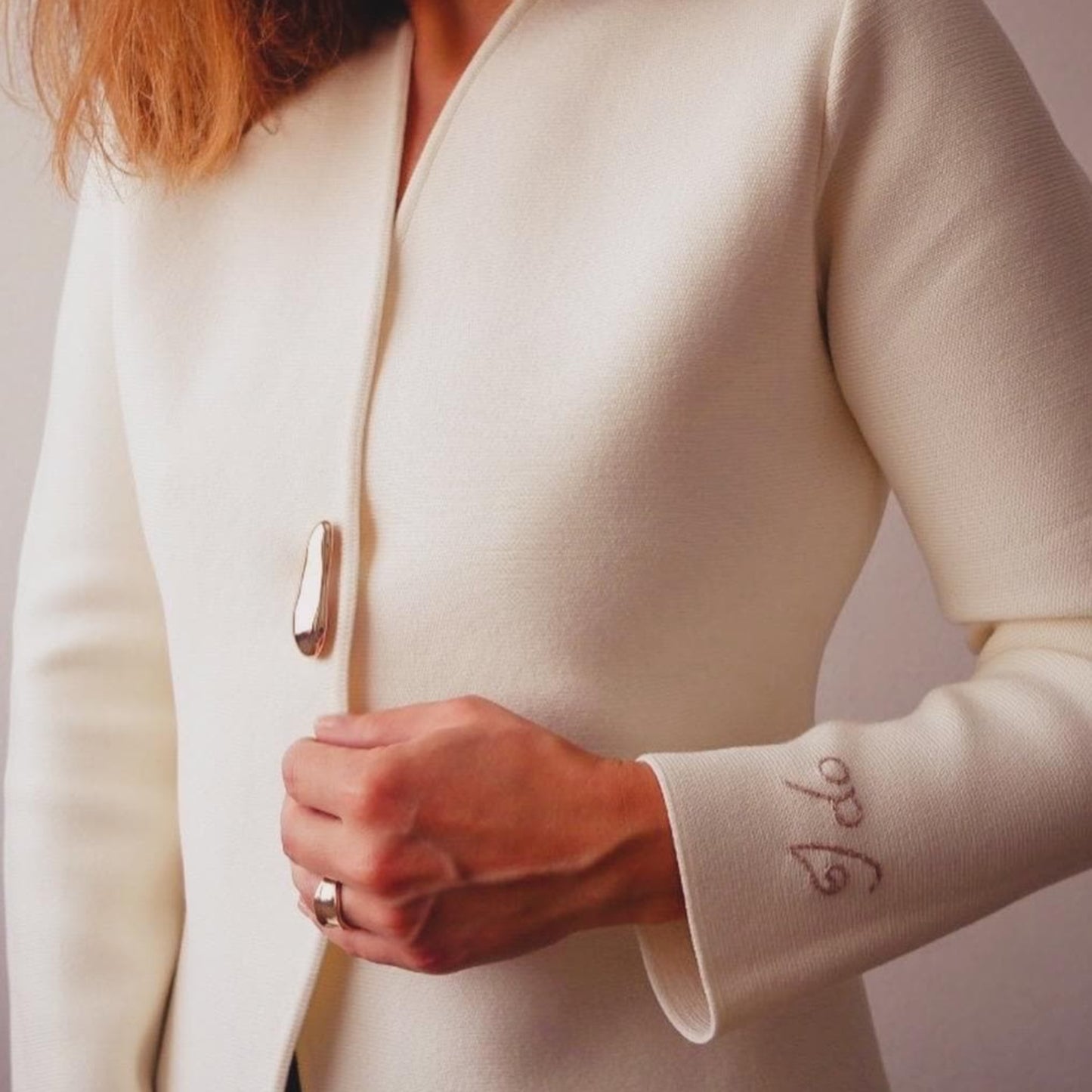 Close-up of a person wearing a white coat with visible text on the sleeve against a plain background