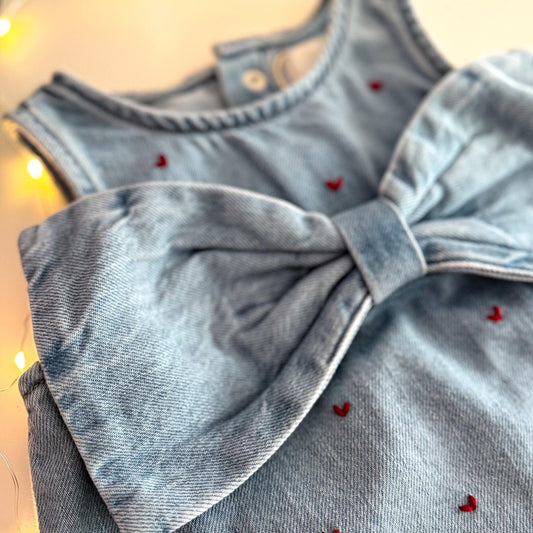 Light blue denim dress with a large bow detail on a blurred background