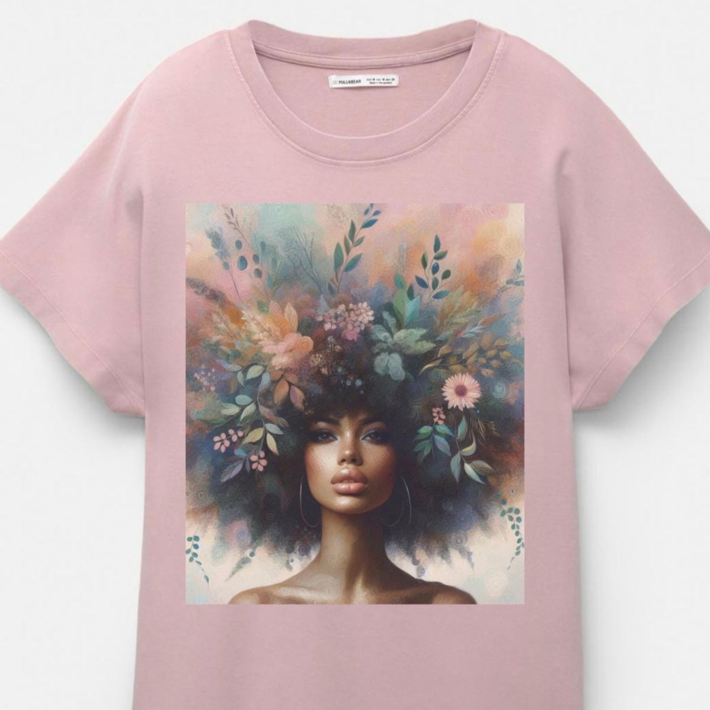 Pink t-shirt with a graphic of a woman with flowers in her hair on a white background