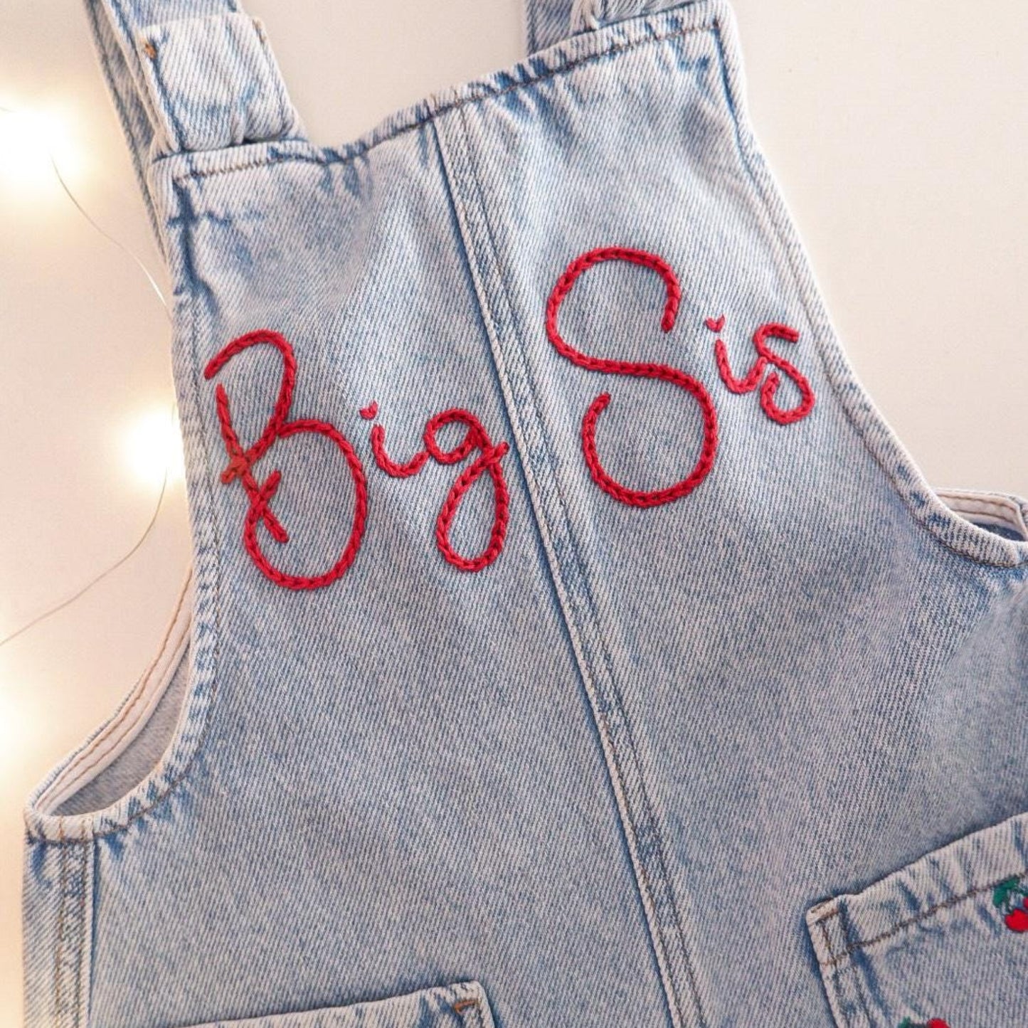 Denim overall dress with 'Big Sis' embroidery on a light background