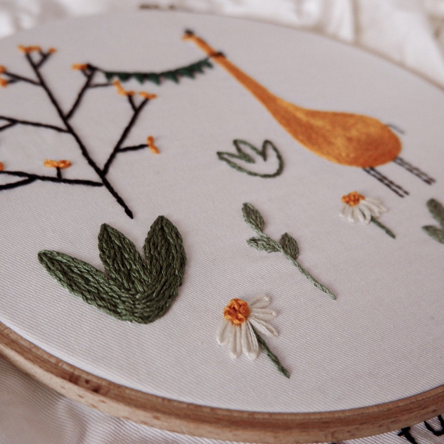 Embroidery hoop with floral and botanical designs on a white background