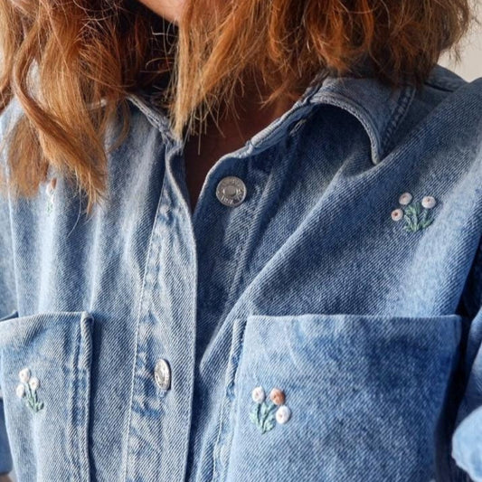Blue denim jacket with floral embroidery on a person wearing it.