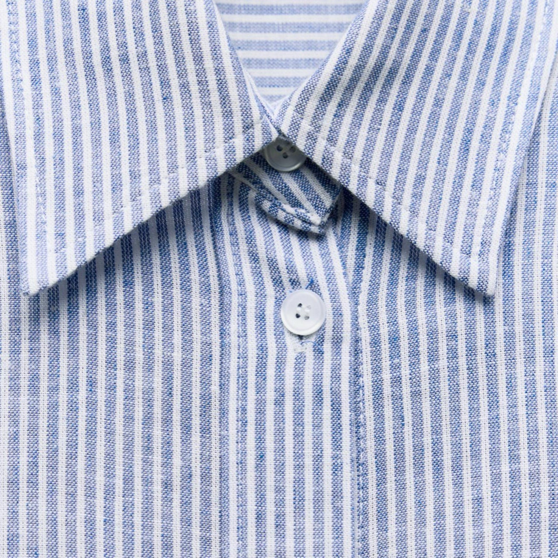 Close-up of a blue and white striped shirt with a button detail.