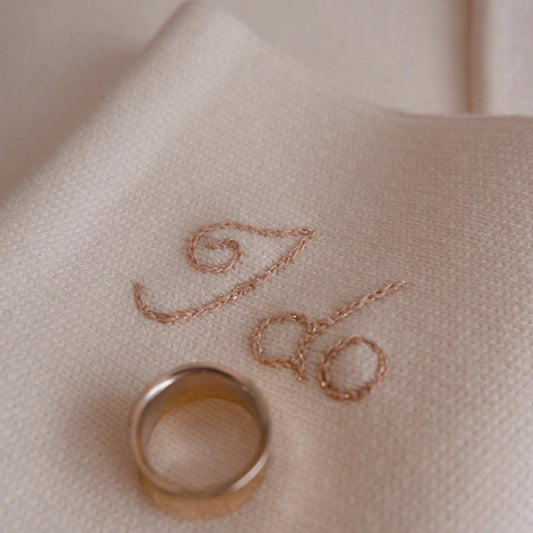 Rose gold ring on a beige fabric with embroidered initials