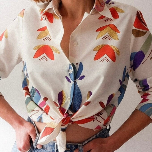 A close-up of a hand-embroidered cotton shirt with colorful floral patterns on a white background.