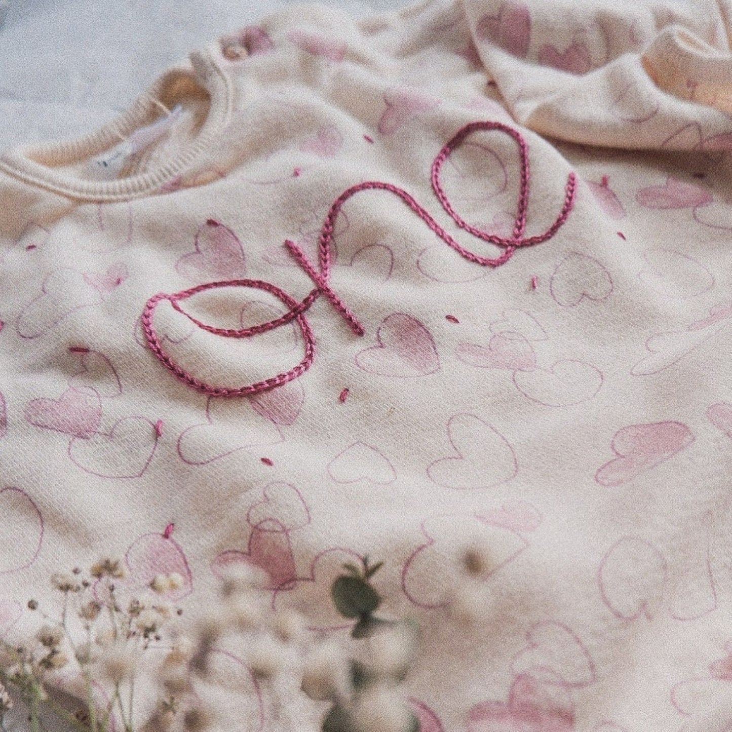 Children's clothing with 'love' embroidered in pink on a light background