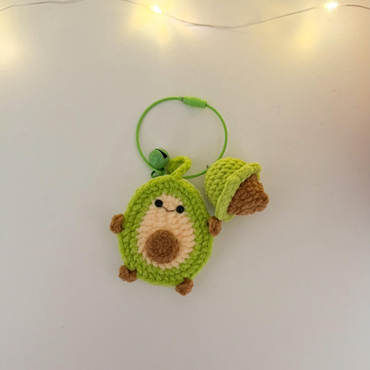Crocheted avocado-shaped keychain on a white background with string lights.