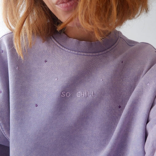 A close-up image of a purple sweatshirt with the text 'SO CHILL' embroidered on the front.