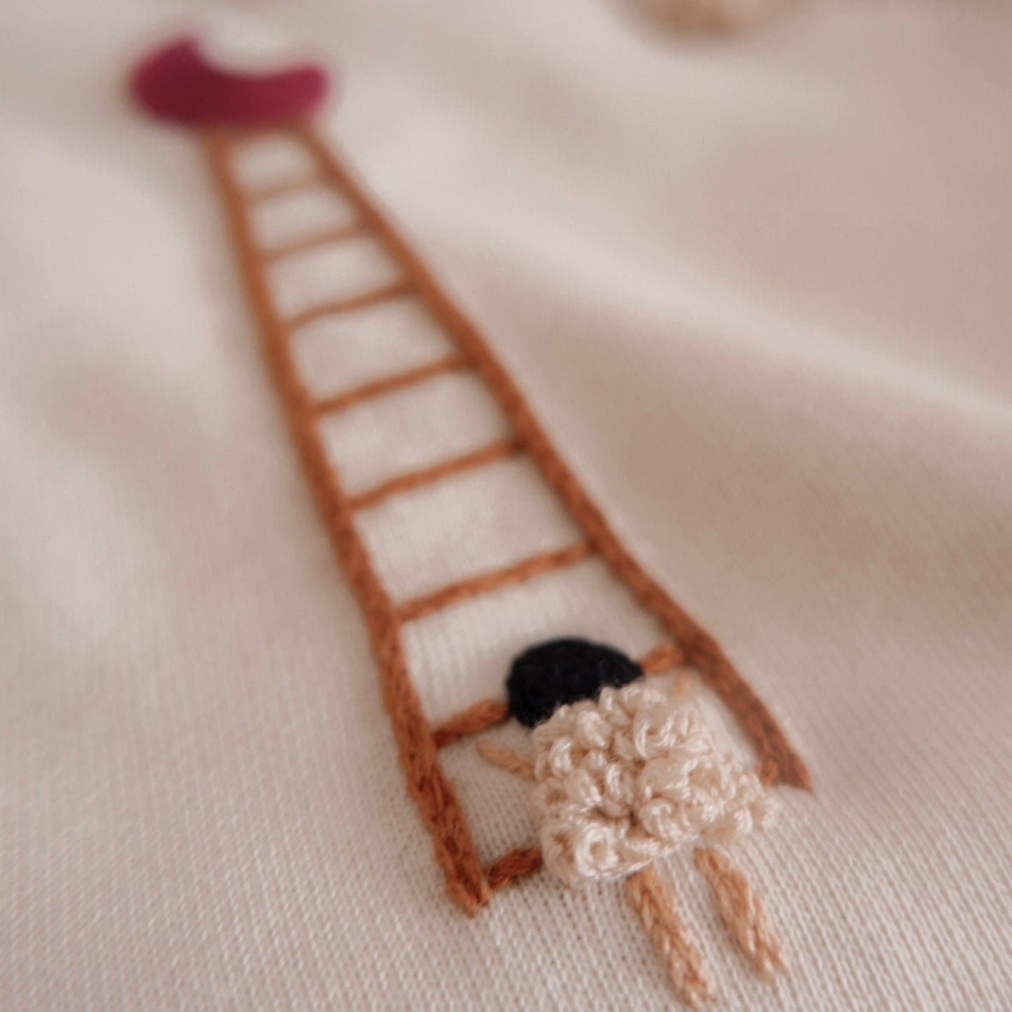 Embroidered design of a girl climbing a ladder on fabric