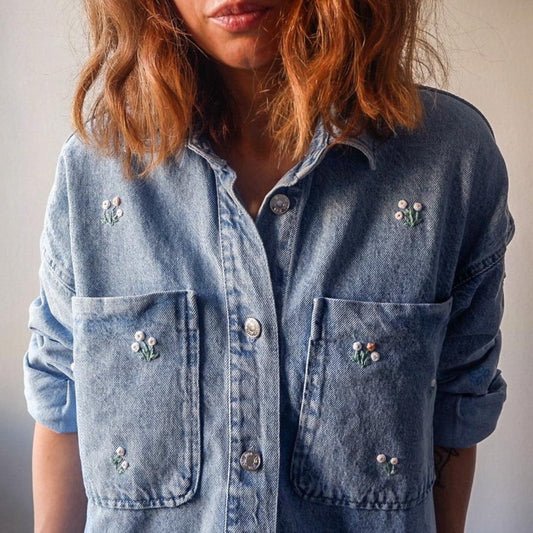 Denim shirt with floral embroidery on a plain background